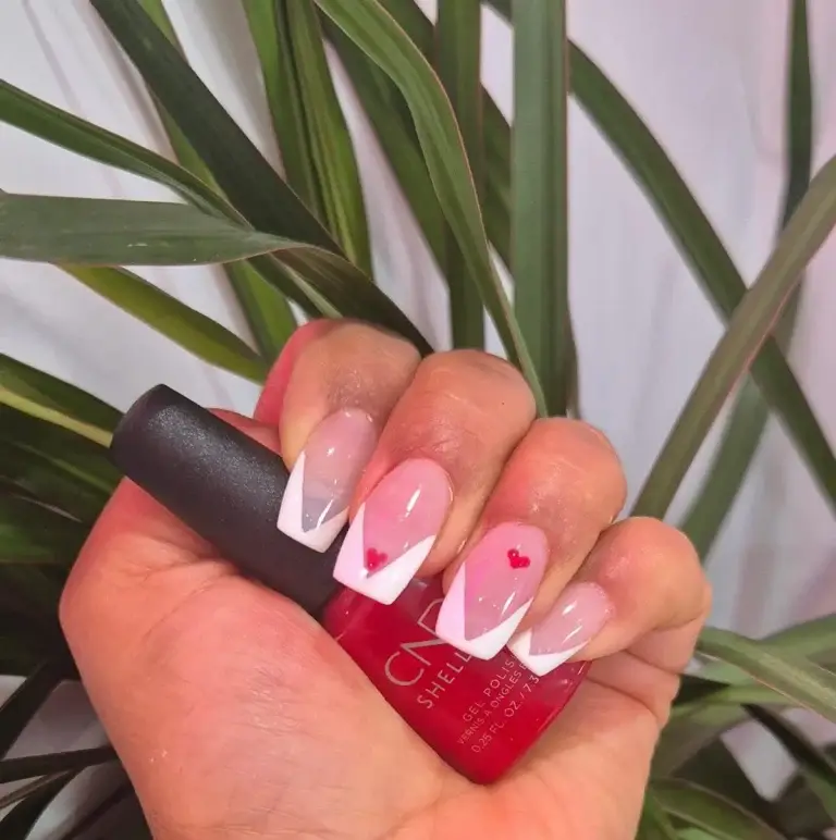 White French-tip nails with delicate red heart nail art at Bhawani Beauty